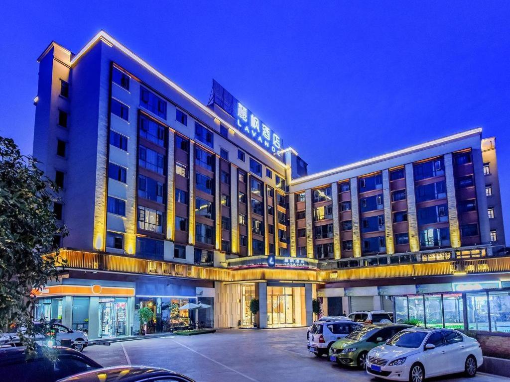 南充Lavande Hotel Nanchong Xihua Shida的停车场内停放汽车的大型建筑