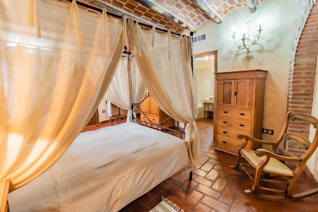 阿兰赫Hotel Rural La Sinforosa的一间卧室配有一张天蓬床和一把椅子