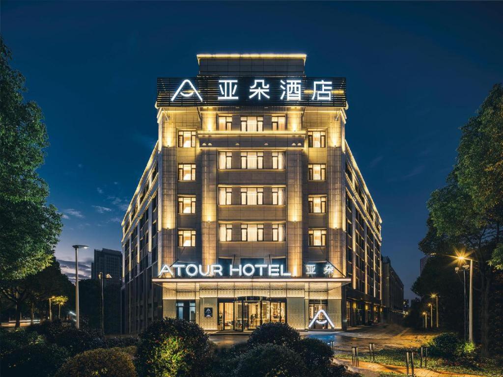 苏州Atour Hotel Suzhou Campus Town Yuexi Metro Station的一座四层楼的酒店,上面有标志