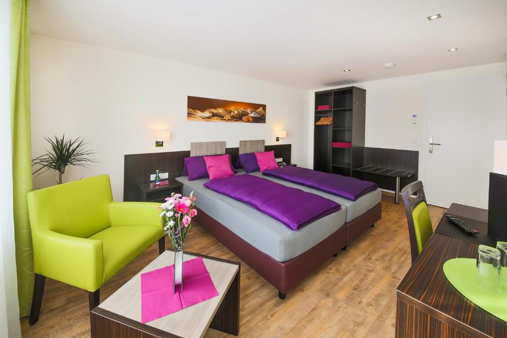 腓特烈港Hotel Gästehaus Stock Zimmer Brotkörble的一间卧室配有一张大床和一张绿色椅子
