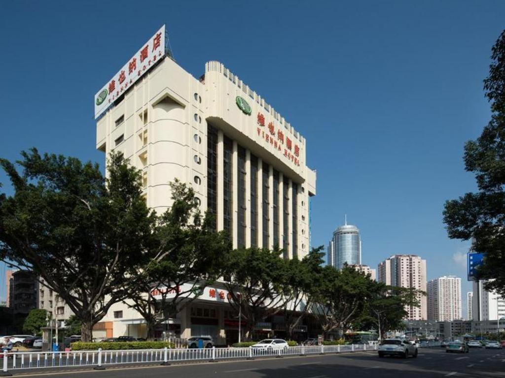 惠州Vienna Hotel Guangdong Huizhou Huabianling Square的一座白色的大建筑,上面有标志