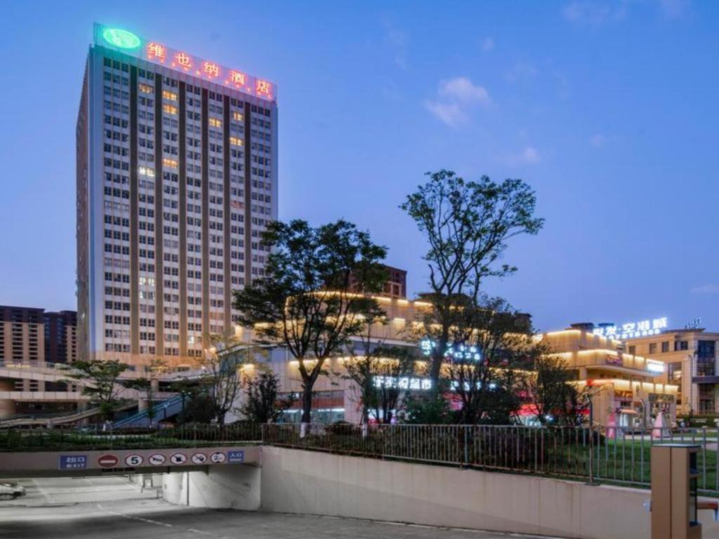 YanglinVienna Hotel Kunming Dianzhong New District的一座高大的建筑,城市里灯火通明