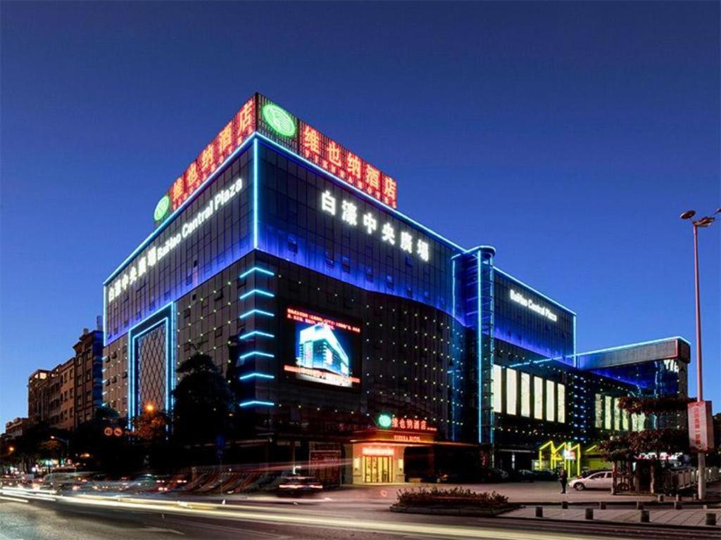 ShatangVienna Hotel Guangdong Dongguan Humen High-Speed Railway Station的一座大型建筑,上面有蓝色的灯光