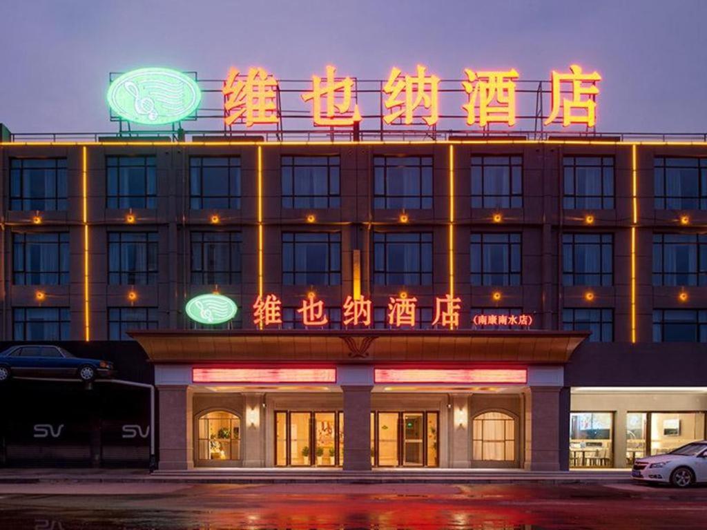 南康Vienna Hotel Ganzhou Nankang District Center的上面有 ⁇ 虹灯标志的建筑