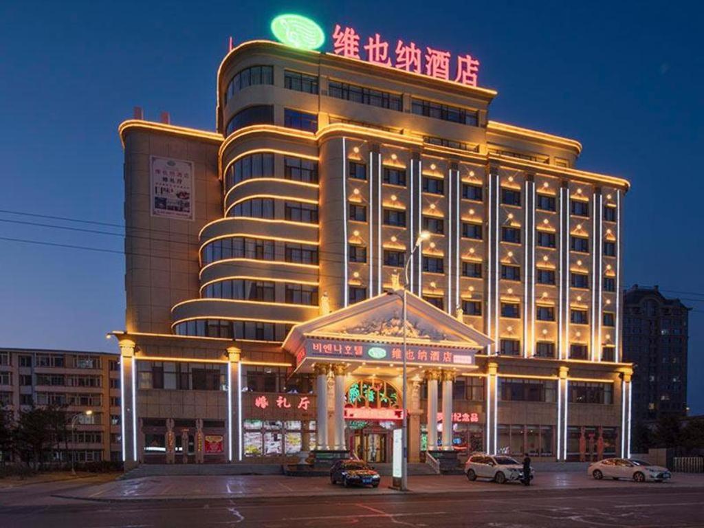 珲春Vienna Hotel Jilin Huichun Yadu Huayuan的一座酒店大楼,上面有标志