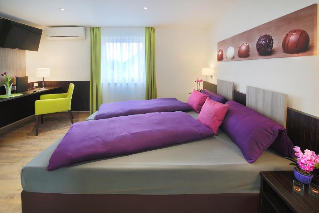 腓特烈港Hotel Gästehaus Stock Zimmer Trüffeleckle的卧室内的一张带紫色枕头的大床