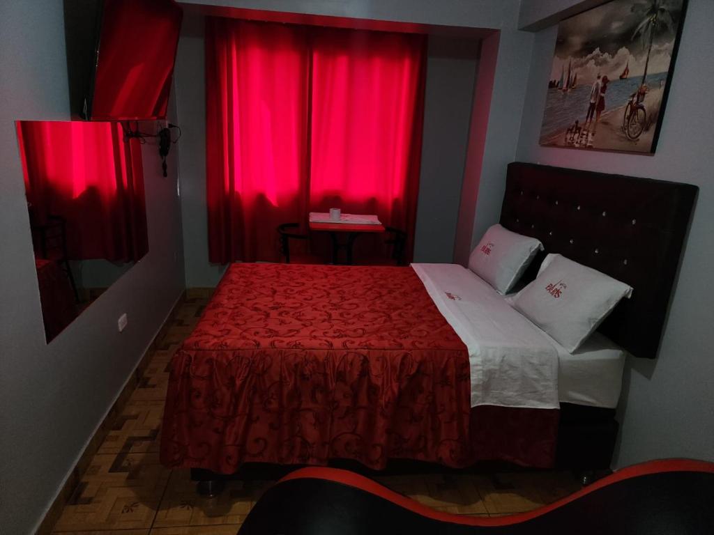 利马hostal paris的一间卧室配有红色窗帘和一张红色毯子