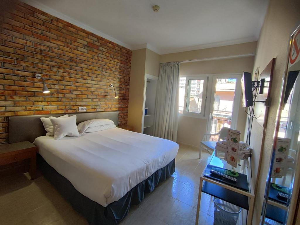 埃尔阿雷纳尔银海旅馆的一间卧室设有一张大床和砖墙