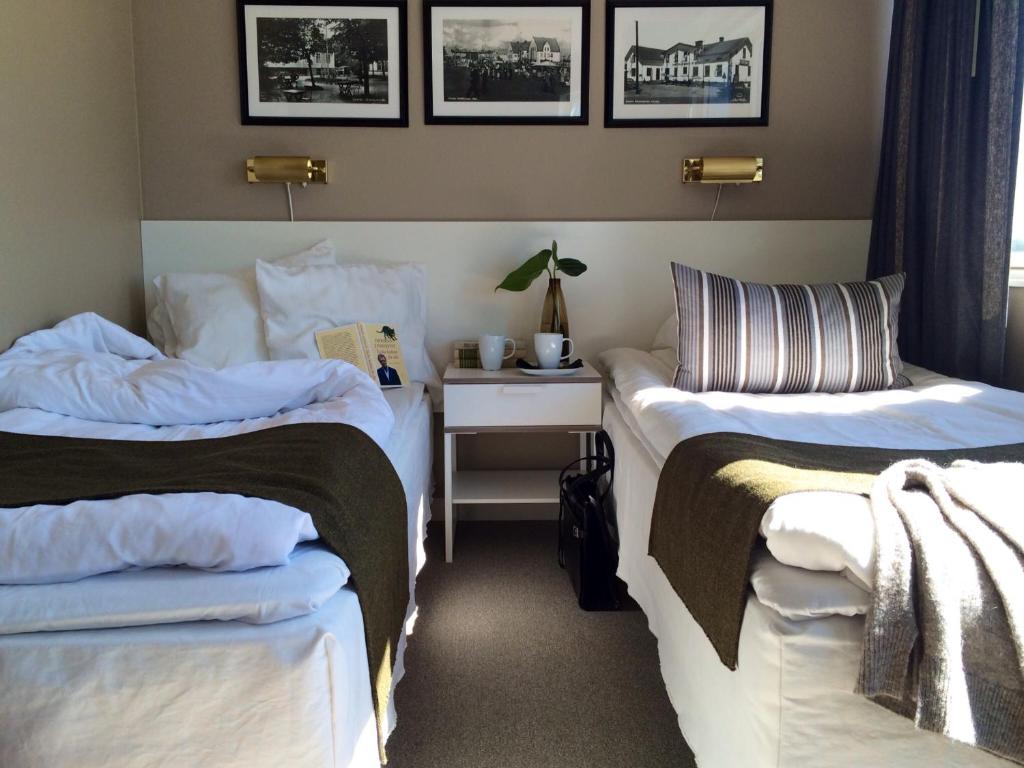 永比加瓦伦酒店的配有2张床的客房,配有带床头柜的桌子