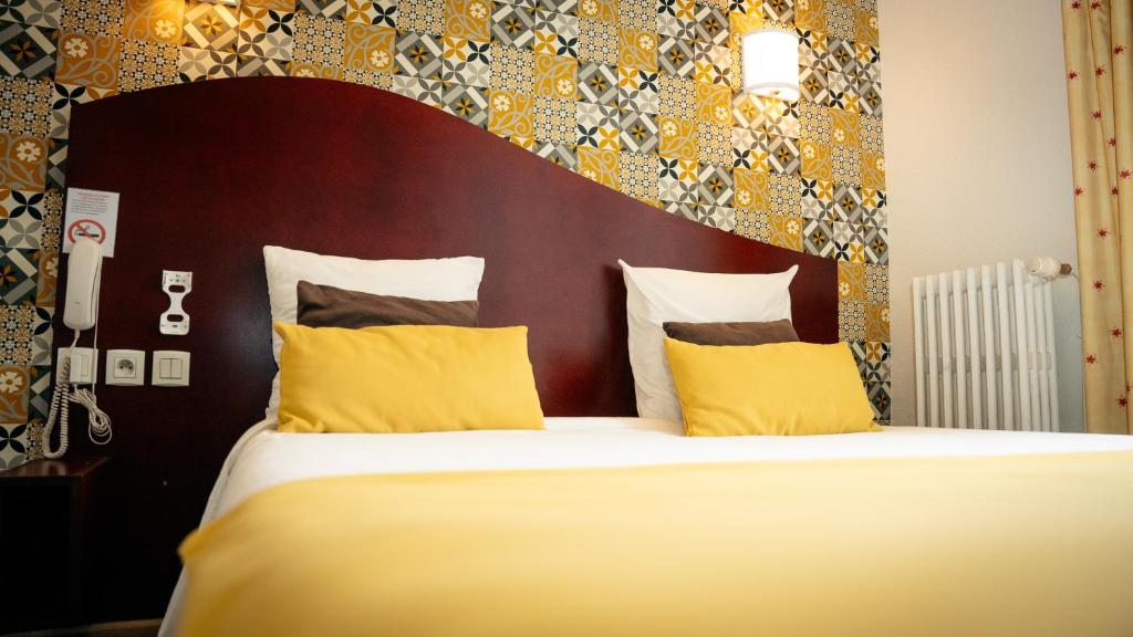 克莱蒙费朗雷康梅尔坎酒店的一间卧室配有一张带黄色枕头的大床
