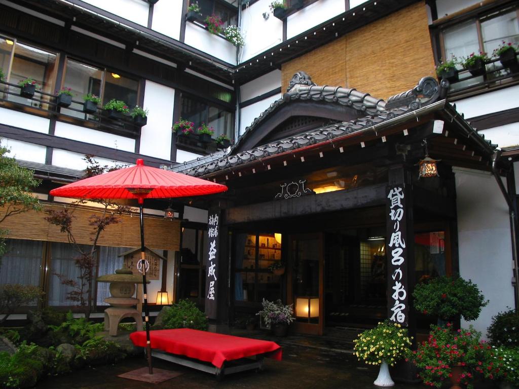 草津益成屋日式旅馆的大楼前的红伞和长凳
