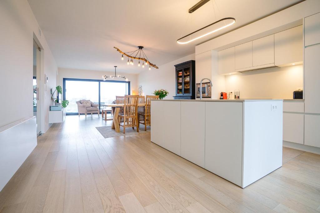 奥斯坦德Vakantieappartement Oosteroever Oostende的开放式厨房和带白色橱柜的用餐室。