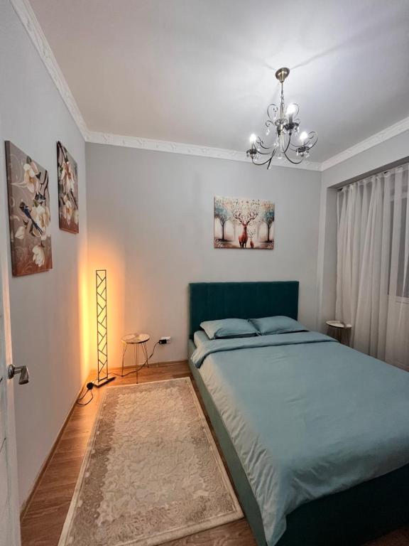 阿拉木图2-х комнатная в Золотом квадрате的一间卧室配有一张绿色的床和吊灯。