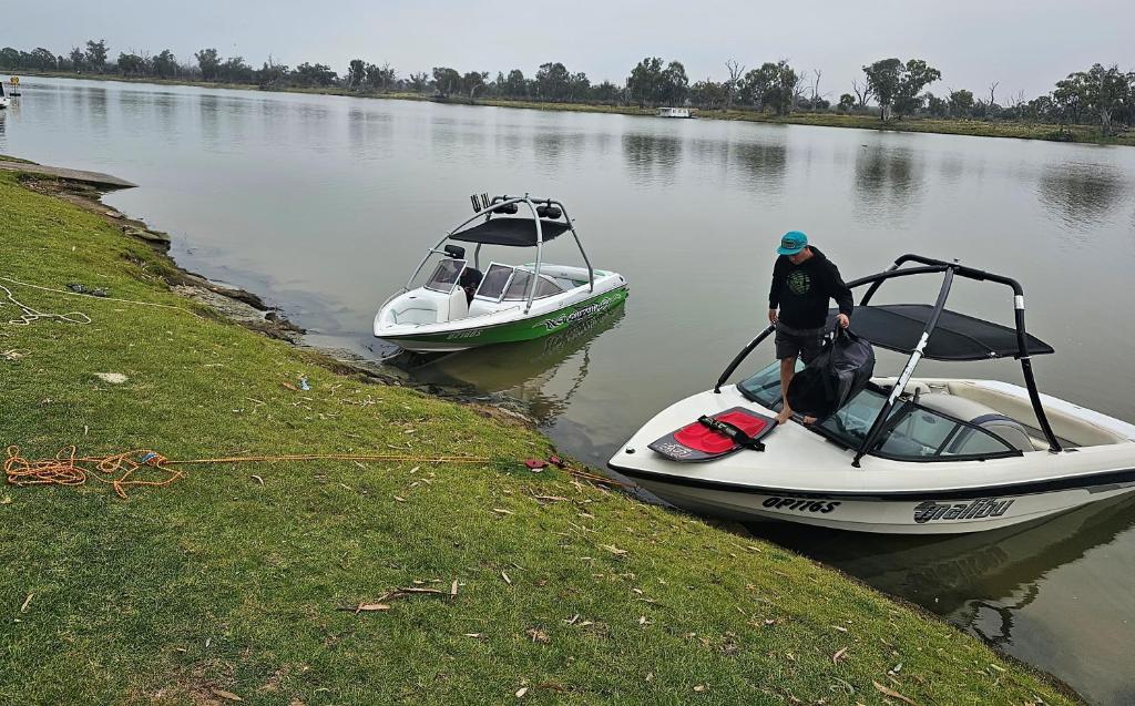 WaikerieRiverview Haven的站在水中的船上的男人