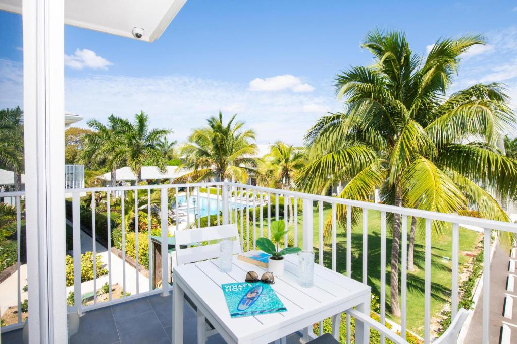 西湾Summertime Suites #54的一个带桌子和棕榈树的白色阳台