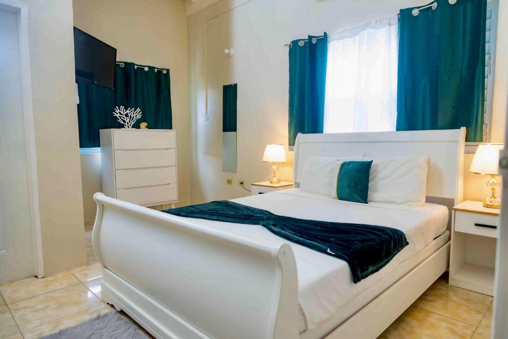 拉纳韦贝Emerald inn at runaway bay的卧室配有白色的床和蓝色窗帘