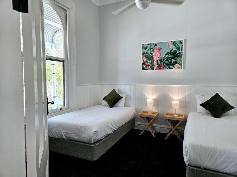 贝纳拉Palm Cottage的一间设有两张床和两张台灯的桌子的房间