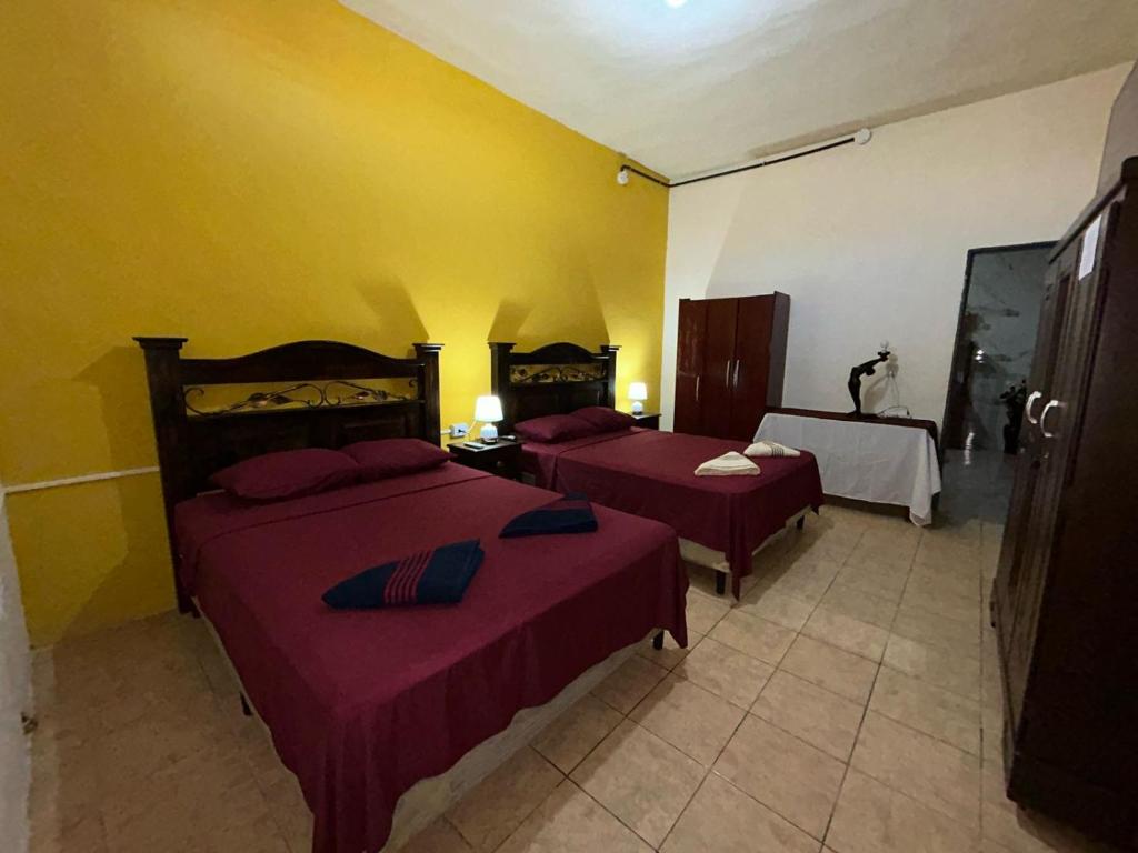 弗洛勒斯Casa Maya Itza的黄色墙壁客房的两张床