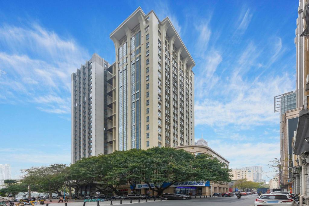 广州WAIFIDEN Duplex Hotel Apartment Zhongyong Jinyu Branch的一座高大的白色建筑,前面有一棵树