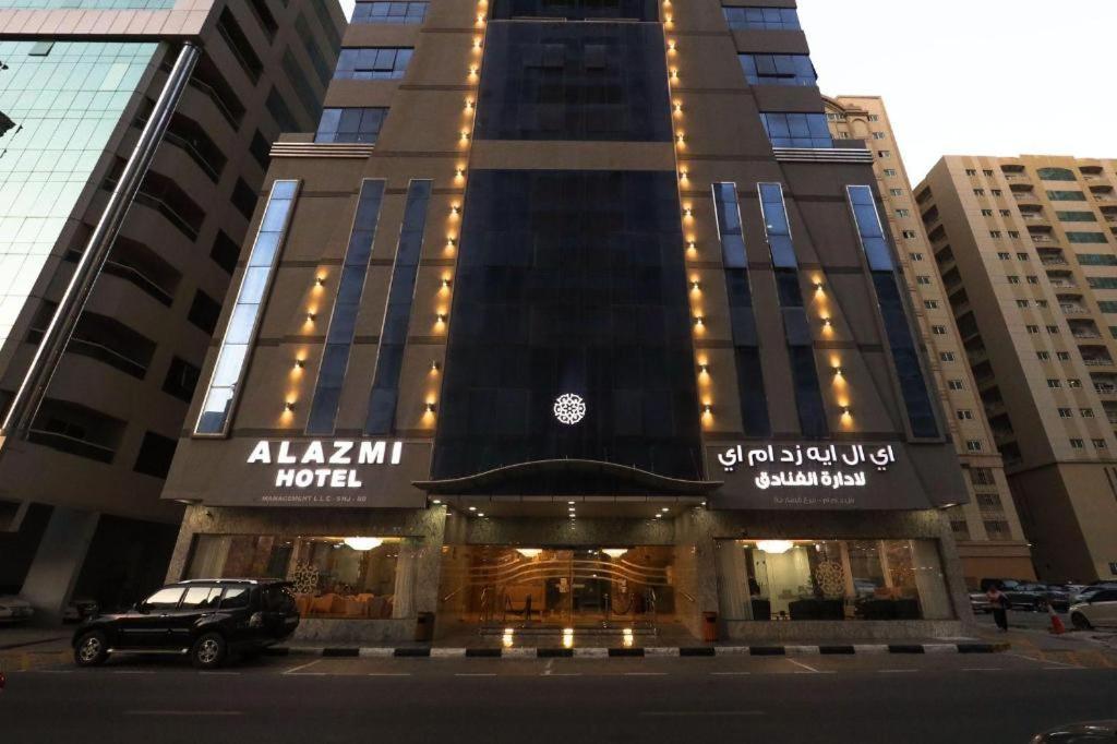 Al KhānALAZMI HOTEL的前面有停车位的建筑