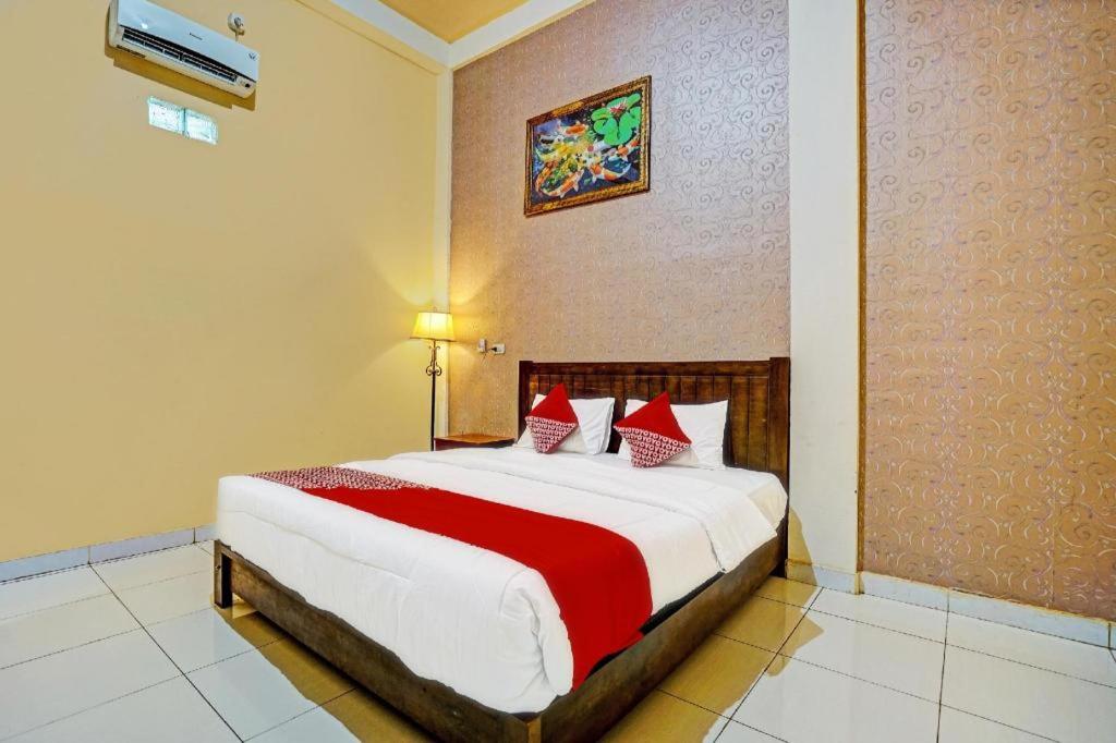 占碑市OYO 92024 Green Hotel的一间卧室配有一张带红色枕头的大床