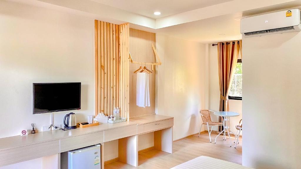 浦阿น่าน ม่วนใจ Nan Muanjai Hotel的酒店客房设有一张桌子、一台电视和一张桌子。