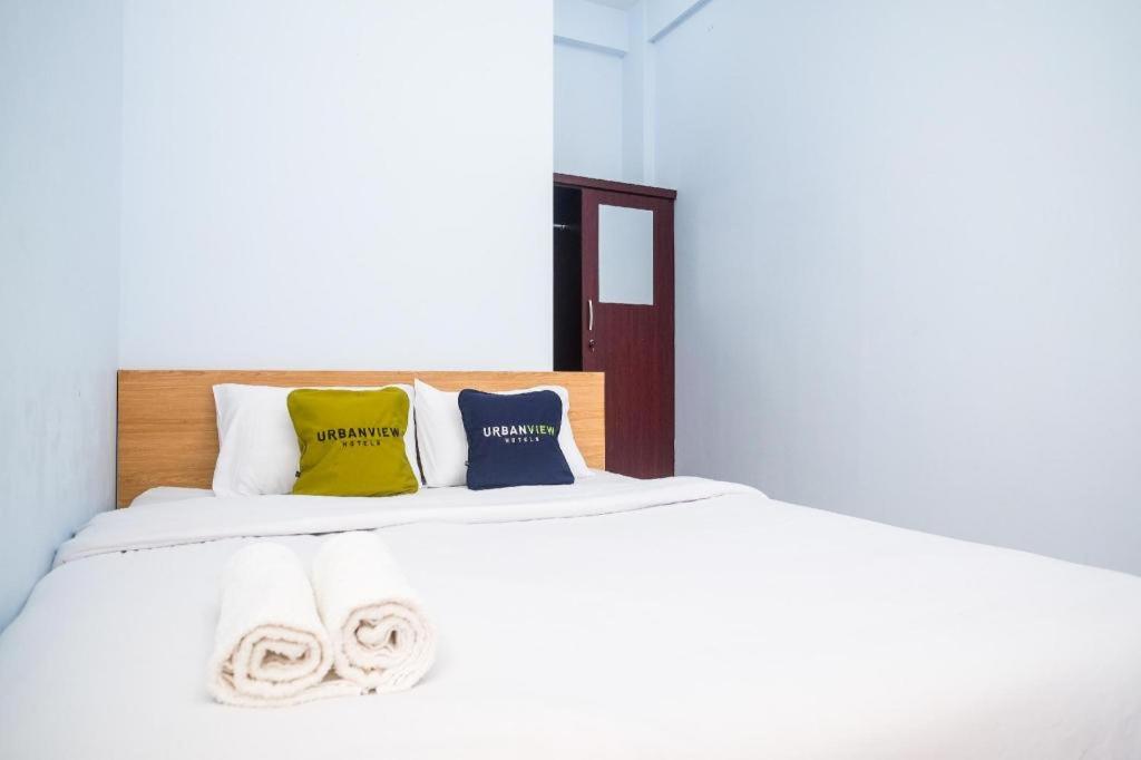 LaweanUrbanview Syariah Wisma Nabil Solo的白色的床,配有色彩缤纷的枕头和毛巾