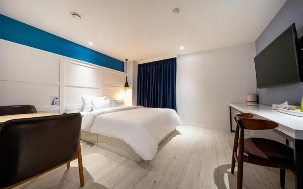 原州市Wonju Bellino Hotel的卧室配有一张白色大床和一张书桌