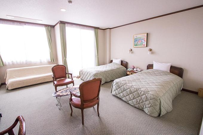 都城市ホテル中山荘的一间卧室设有两张床、椅子和窗户