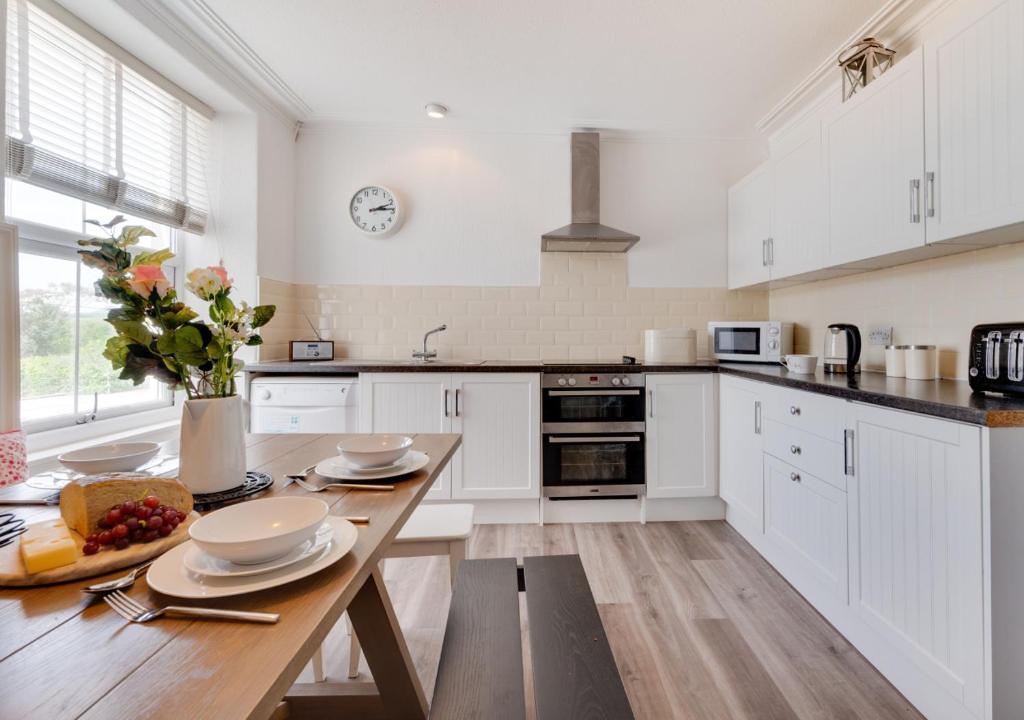 阿伯索赫Bronwydd的厨房配有白色橱柜和木桌