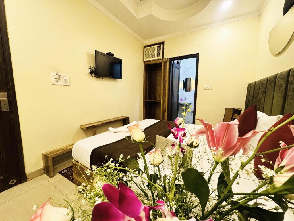 新德里Staybook Hotel Jai Balaji, Paharganj, New Delhi Railway Station的配有床和鲜花的酒店客房