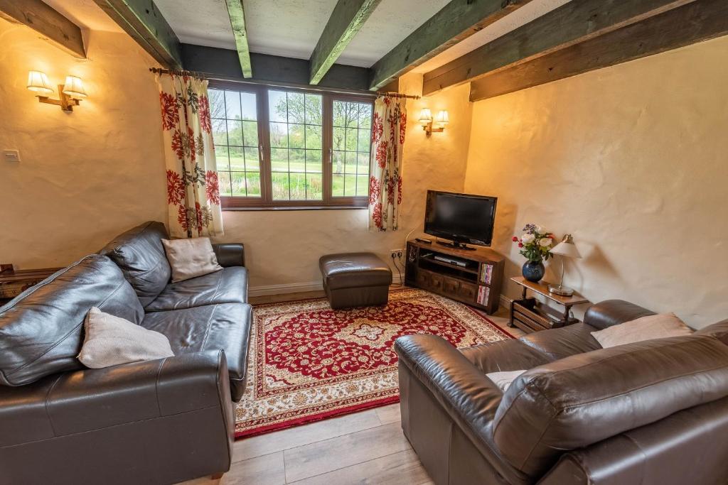伍拉科姆Lakeside Cottage的客厅配有两张真皮沙发和一台电视机