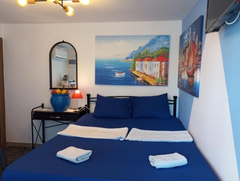 马科普隆4Seasons Suites Paradise Near Airport的一间卧室配有一张蓝色的床、一张桌子和一幅画