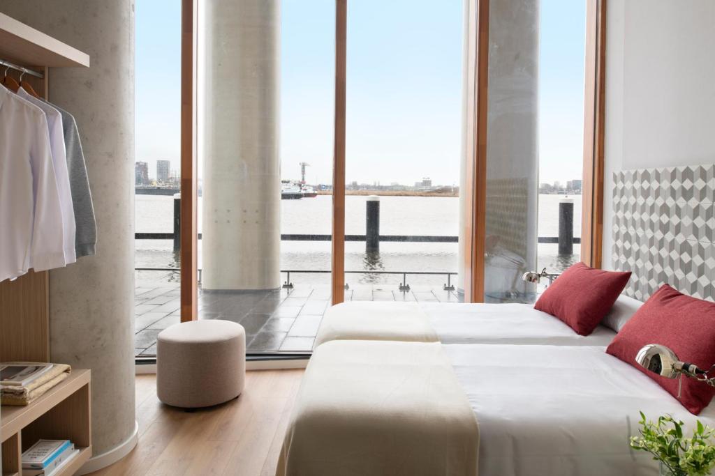阿姆斯特丹Eric Vökel Boutique Apartments - Riverfront Suites的一间卧室设有两张床和大窗户