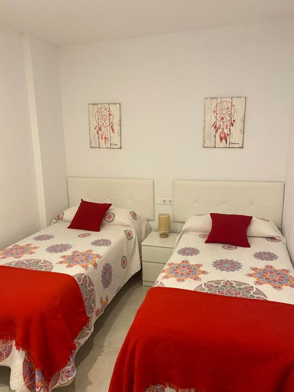 塔里法TURISMO LOS LANCES TARIFA( PARKING GRATUITO)的白色客房的两张床,配有红色床单