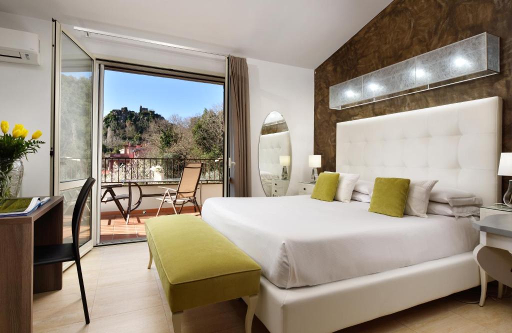 特雷维尼亚诺罗马诺Hotel Recostano Residence的一间带一张白色大床的卧室和一个阳台
