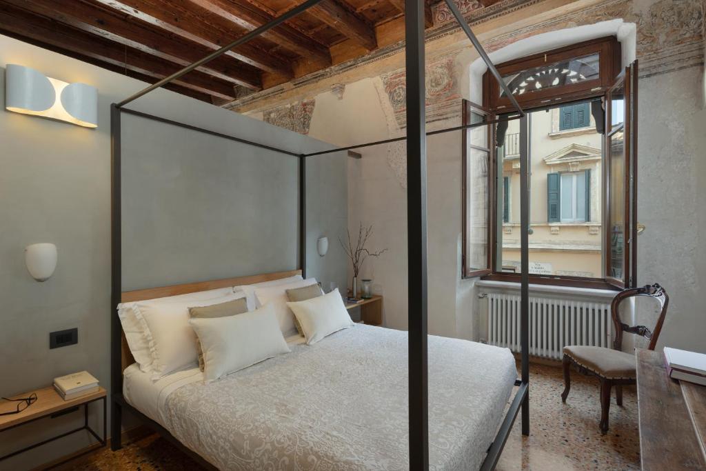 维罗纳罗佳玛姬儿公寓的一间卧室设有天蓬床和窗户。