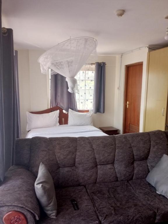 内罗毕Best suites Mvuli的卧室配有一张床,窗户前配有一张沙发