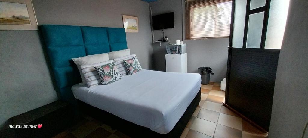 德班Rato Thato Guest House的一间卧室配有一张白色的床和蓝色床头板