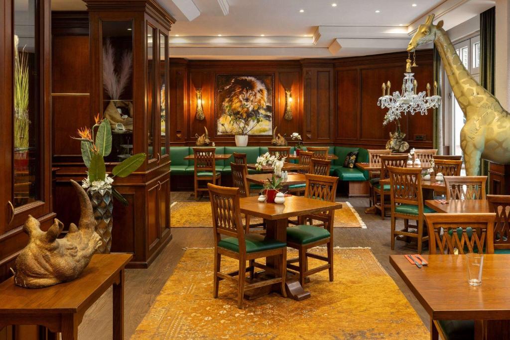莱比锡Amedia Hotel &amp; Suites Leipzig, Trademark Collection by Wyndham的餐厅拥有长颈鹿壁画和桌椅