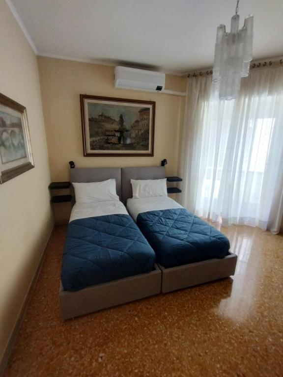 罗马Appartamento Fiore Roma Cinecittà的一间卧室设有两张带蓝色床单的床和窗户。