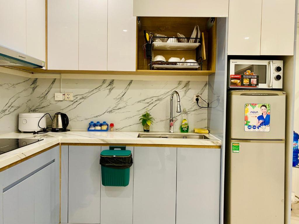 Long BìnhVinhomes Grand Park Homestay的厨房配有白色橱柜和冰箱。
