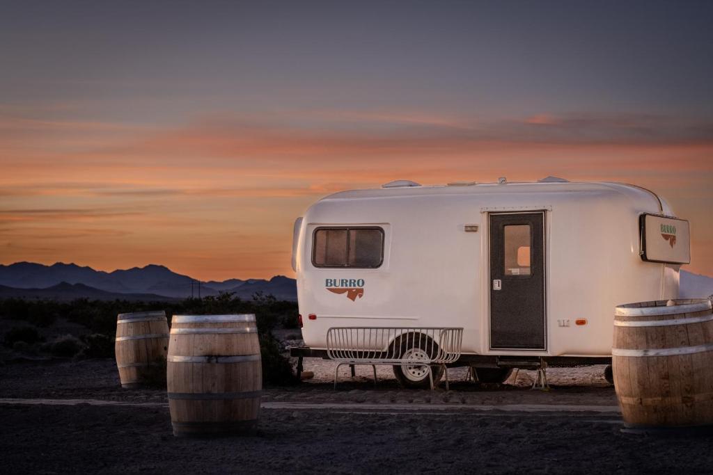 阿马戈萨山谷Tarantula Ranch Campground & Vineyard near Death Valley National Park的停在一个有桶的田野上的白色拖车