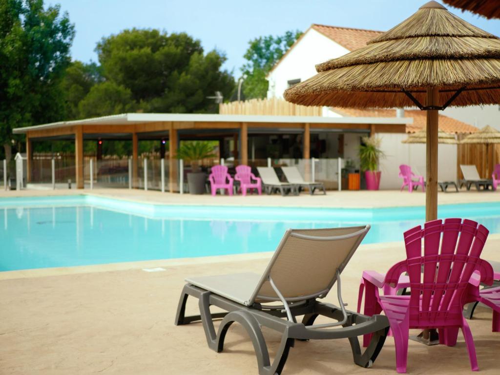 Saint-NazaireCamping Saint-Nazaire的游泳池旁的一对椅子和一把遮阳伞