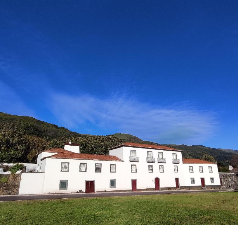 Fajã de Santo AmaroQuinta dos Mistérios- Turismo de Habitação的山坡上一座白色的建筑,有红色的屋顶