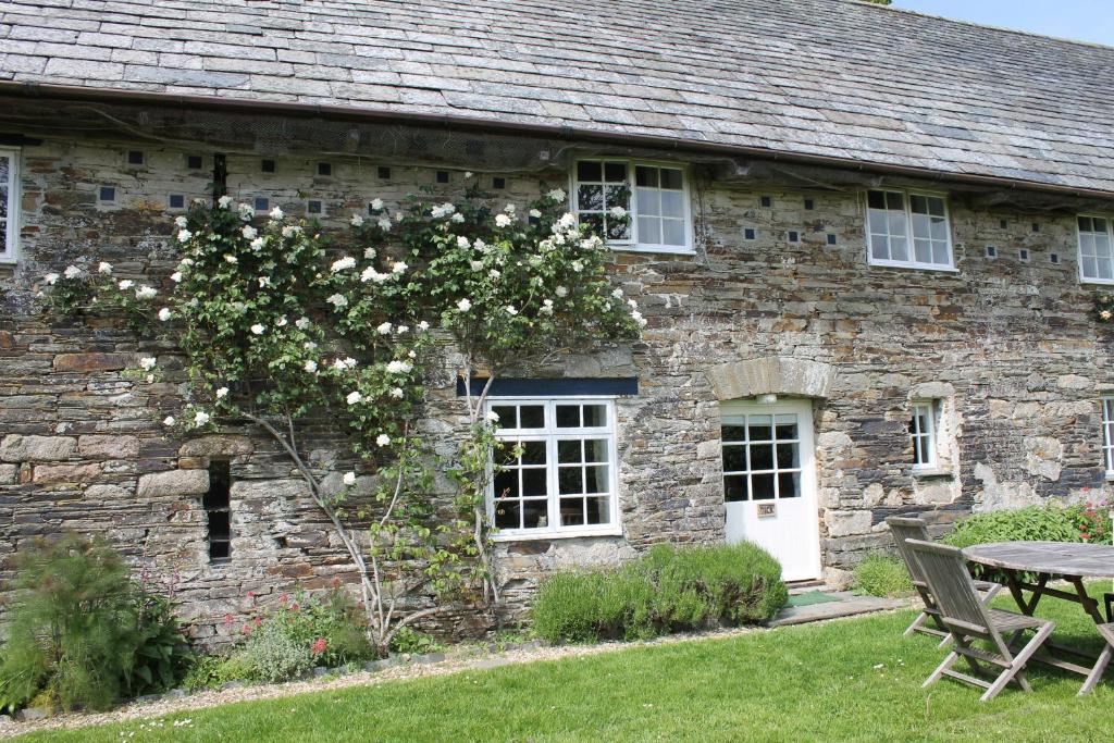 博德明Dick Cottage的石头房子,有桌子和一棵白色花树