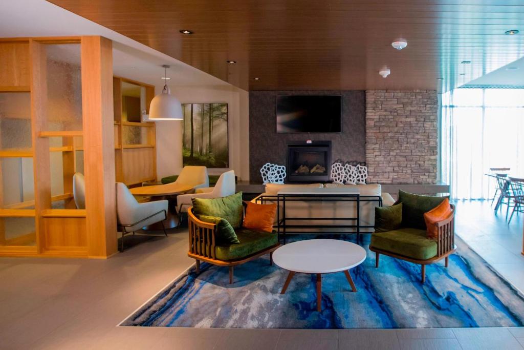 亚历山德里亚Fairfield Inn & Suites By Marriott Alexandria的客厅配有椅子、桌子和壁炉