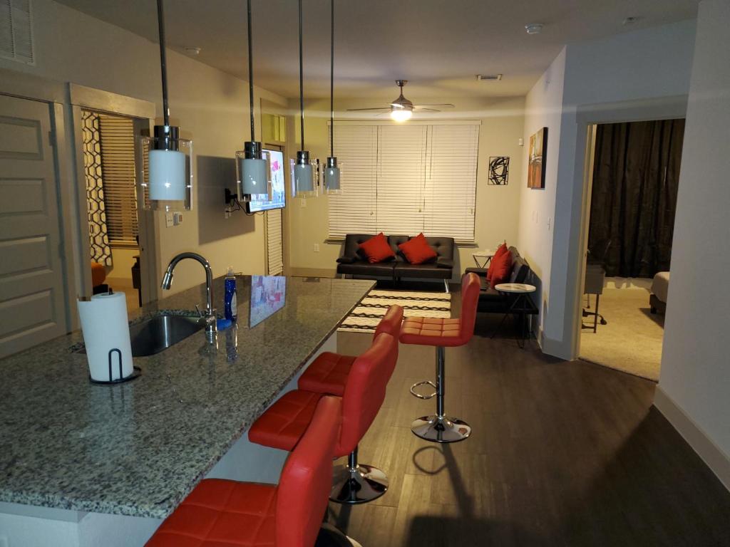 休斯顿Smart automation apartment in Woodlake/Westheimer的厨房以及带柜台和红色椅子的客厅。