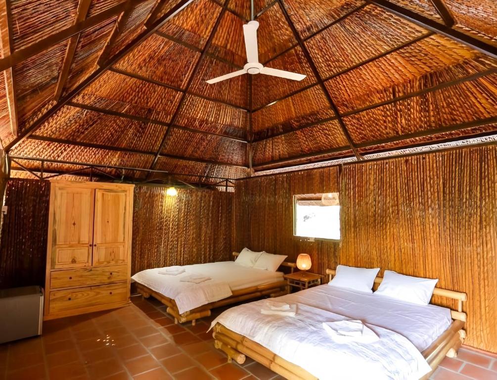 芹苴丹辛民宿的一间位于稻草屋顶的卧室,配有两张床