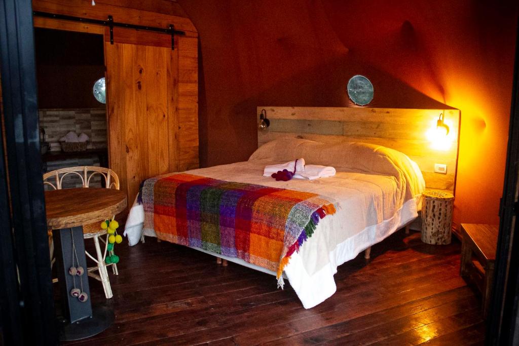 Tafí ViejoWillkay Glamping Raco Tucumán的一间卧室配有一张带彩色毯子的床